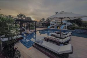 a swimming pool with lounge chairs and an umbrella at Aimberê Eco Resort Hotel in Coqueiro