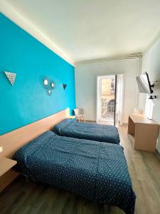 2 camas en una habitación con una pared azul en Hôtel Colisée-Verdun Centre Gare Saint-Roch, en Montpellier