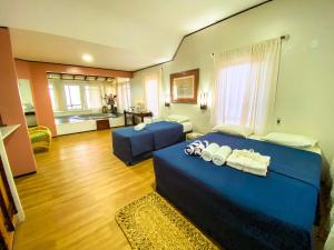 a bedroom with a blue bed and a living room at Aimberê Eco Resort Hotel in Coqueiro