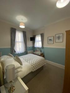 a bedroom with a bed and two windows at Buckingham Lodge Guest House in Torquay