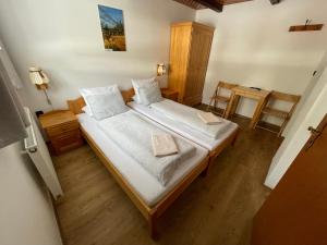 a bedroom with a large bed with white sheets at Pension Hones in Horská Kvilda