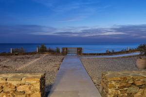 un chemin menant à la plage avec l'océan en arrière-plan dans l'établissement Cape Suites, à Kythnos