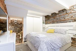 a bedroom with a bed and a stone wall at Antico Basolato House in Catania