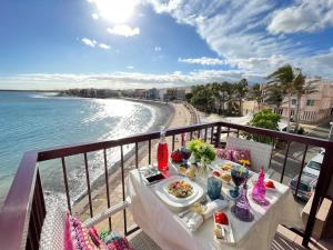 a table on a balcony with a view of the beach at EmyCanarias Primera Línea De Playa in Arinaga