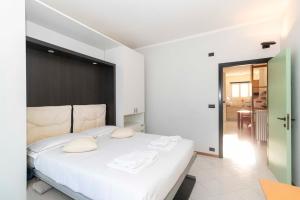a bedroom with a large white bed with white pillows at Mirafiori Balcony Apartment in Turin