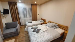 a hotel room with two beds and a chair at Wyspa Mszanka in Mszana Dolna