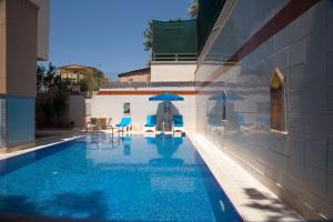 a pool with chairs and an umbrella next to a building at Nasa Flora Hotel in Antalya
