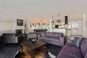a living room with purple couches and a kitchen at Landgoed Hermitage - Villa Euphoria - XXL Zwemspa - Max 10 personen in Ouddorp