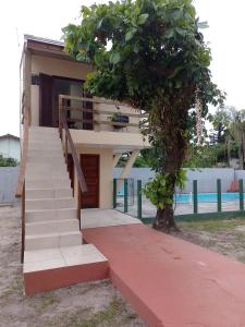 Una casa con escaleras y un árbol delante. en Residencial Lumar, en Itapoa