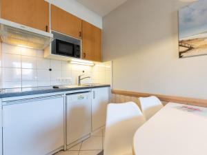 - une cuisine avec des appareils blancs, une table et des chaises dans l'établissement Appartement Beka 15, à Westerland