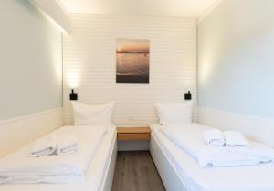 twee bedden in een kamer met witte lakens en handdoeken bij Appartement Beka 15 in Westerland