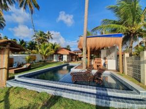 a swimming pool with two benches in front of a house at Club Manguaba Beira Mar in Japaratinga