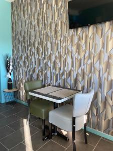- une salle à manger avec une table, des chaises et un mur dans l'établissement Logis - Hôtel et Restaurant Le Sofhotel, à Forges-les-Eaux