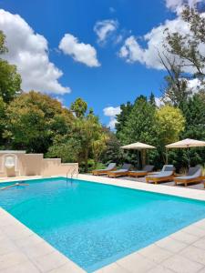 a swimming pool with chairs and umbrellas at Casa de Campo Las Acacias in Tandil