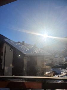 a view of a building with the sun in the sky at Alpenblick Leukerbad in Leukerbad