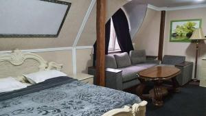 a bedroom with a bed and a chair and a table at Leoton Chernivtsi in Chernivtsi