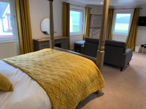 1 dormitorio con cama, silla y espejo en Lamlash Bay Hotel, en Lamlash
