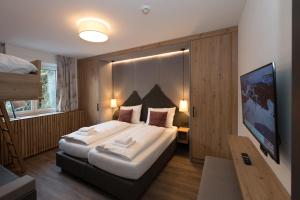 a hotel room with a large bed and a tv at Der Zirmhof in Saalbach in Saalbach Hinterglemm