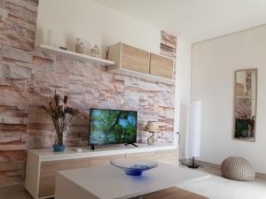 un salon avec une télévision sur un mur en briques dans l'établissement Appartamento Vacanze La Maddalena, à La Maddalena