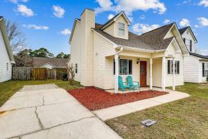 a white house with two blue chairs in the yard at Sea Breeze Cottage in Gulf Breeze