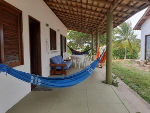 a hammock on the porch of a house at CHALE PERTO DA PRAIA COM DUAS SUITES E VARANDAO in Pacatuba