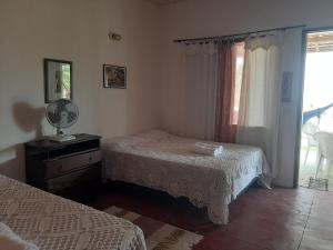 a bedroom with two beds and a window at CHALE PERTO DA PRAIA COM DUAS SUITES E VARANDAO in Pacatuba