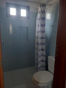 y baño con aseo y ducha con azulejos azules. en CHALE PERTO DA PRAIA COM DUAS SUITES E VARANDAO, en Pacatuba