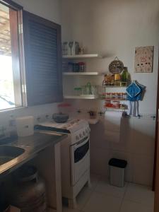 a kitchen with a stove and a sink and a window at CHALE PERTO DA PRAIA COM DUAS SUITES E VARANDAO in Pacatuba