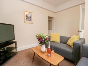 a living room with a couch and a table with flowers at Combe Cottage in Millom