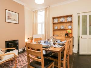 a dining room with a table and chairs and a fireplace at Combe Cottage in Millom