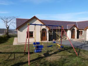 a yard with a swing set in front of a house at Blaengader Cottages - Enlli in Aberystwyth