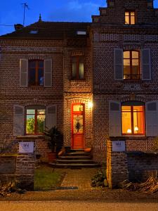 une maison en briques avec une porte rouge la nuit dans l'établissement Le Jardin, chambres d'hôtes en Baie de Somme, à Cahon