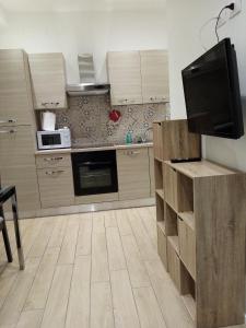 een keuken met houten kasten en een flatscreen-tv bij Appartamento Turistico "ortensia" in Ancona
