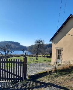 una recinzione accanto a una casa con un lago sullo sfondo di Gite de l'étang Rangère a Villapourçon