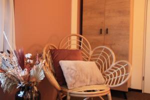 ein Zimmer mit zwei Korbstühlen und einer Vase mit Blumen in der Unterkunft Maison Bellefleur B&B - Pension in Renesse