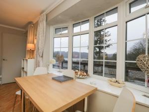 a dining room with a table and large windows at Lake View in Windermere