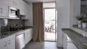 a kitchen with white cabinets and a sliding glass door at Ona Campanario in La Cala de Mijas
