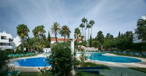 a swimming pool with palm trees and chairs in a resort at Ona Campanario in La Cala de Mijas