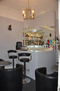 a bar with black chairs and a counter with a mirror at Hotel Peppers in Torquay