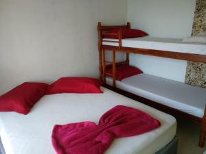 two beds with red pillows on them in a room at Residencial Alexandre - Com piscina aquecida in Matinhos +28 photos