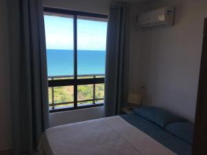 a bedroom with a bed and a large window at Praia Bela, vista mar. Novo! in Pitimbu +38 photos