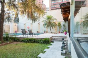 un patio trasero con piscina y una casa en Hotel Embajador en San Miguel de Tucumán