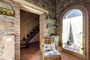 a room with a stone wall and a chair and a window at Appartamento in casale con piscina Casa I Pavoni in Chianni +39 photos