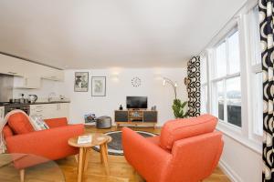 a living room with two orange chairs and a tv at Victoria Apartment 3 in Torquay