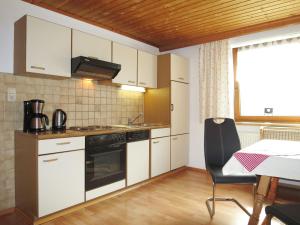 eine Küche mit weißen Schränken, einem Tisch und einem Stuhl in der Unterkunft Apartment Neuner - MHO620 by Interhome in Hippach