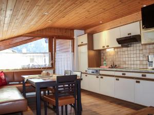 cocina con armarios blancos, mesa y sillas en Apartment Haus Grazia - PTZ154 by Interhome en Prutz