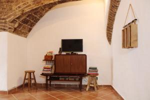 a living room with a tv and a table with stools at Casa da Moeda in Évora