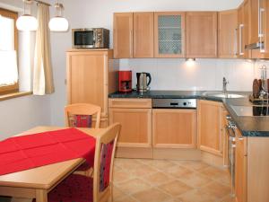 a kitchen with wooden cabinets and a table with a red table cloth at Apartment Köhle by Interhome in Pfunds