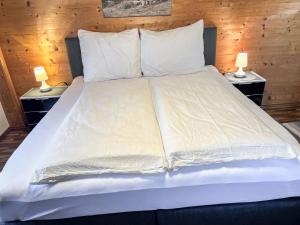 un grande letto con lenzuola e cuscini bianchi di Apartment Gangerhof - KAB208 by Interhome a Kaltenbach