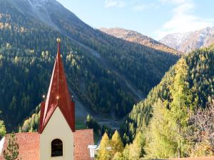 a church with a red steeple in front of a mountain at Apartment Piz Munschuns - SIX100 by Interhome in Spiss